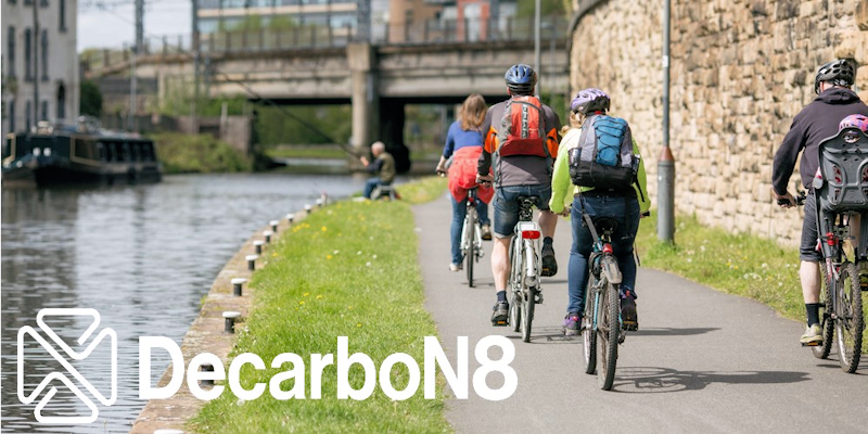 People cycling next to a canal with DecarboN8 logo watermark