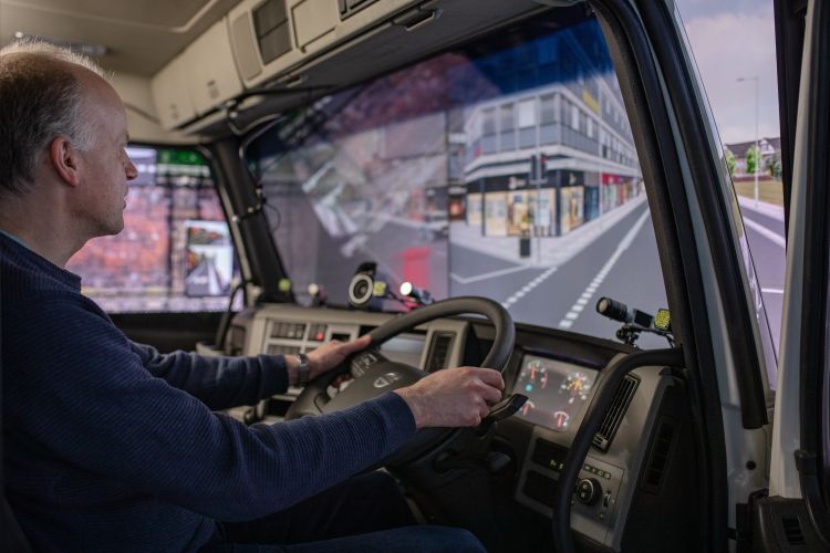 A person sits in a virtual reality driving simulator