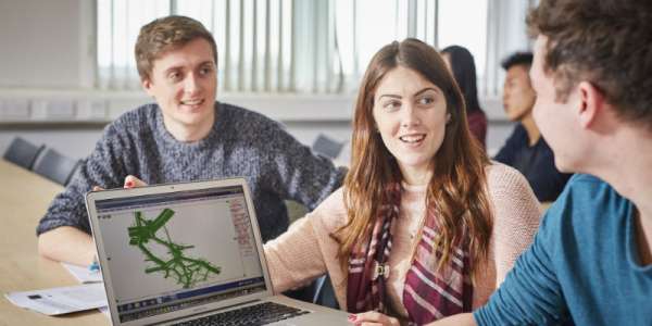 Three undergraduate transport students sit around a laptop, female-presenting student shows a map on screen