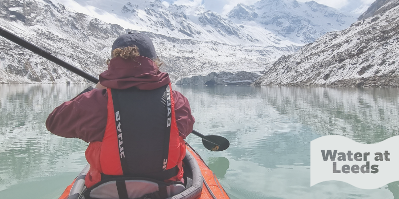Prof Duncan Quincey kayaking in a glacier lake. Mountains are in the background and the water is icy blue. Logo overlay reads 'Water at Leeds'