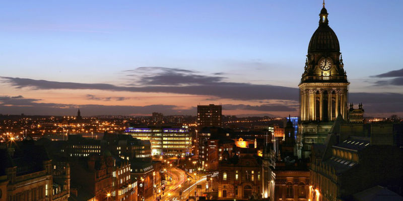 Leeds town hall at night with city lights and sunset sky