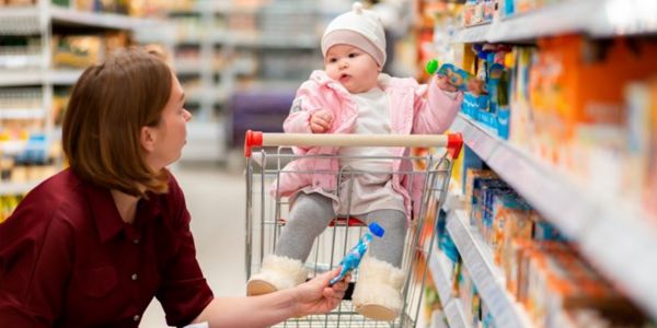 Baby in supermarket trolley, Mum crouching holding out food.