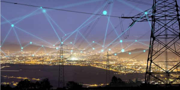 A image of a cityscape at night with a transmission tower/pylon on the righthand side.