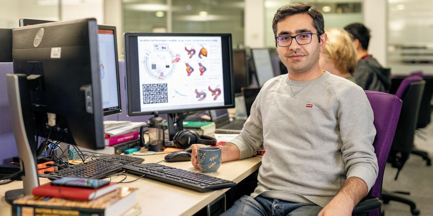 Postgraduate researcher sitting a his research desk and drinking coffee