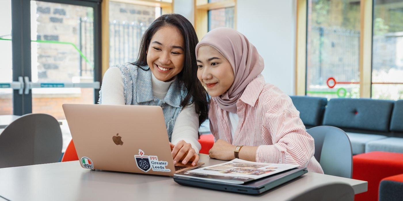 Image of two ITS students working on a laptop in the foyer of the Institute for Transport Studies.