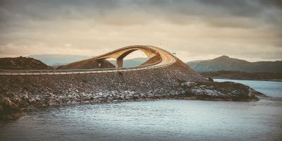 A picturesque view of a Norway sea landscape with a large curved bridge.