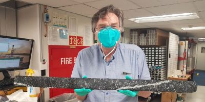 Dr Andrew McCaig holding a long core section of Harzburgite rock from the Earth’s mantle.