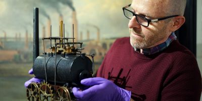 John McGoldrick holding model train, wearing gloves