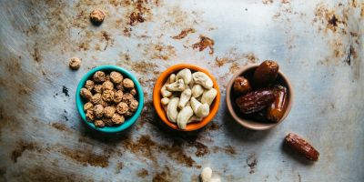 Three small bowls of nuts and dates