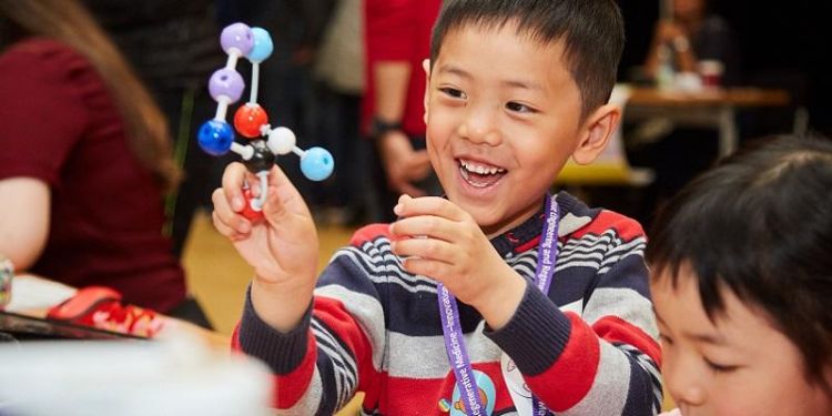 Kid holding a model of a molecule in his hand