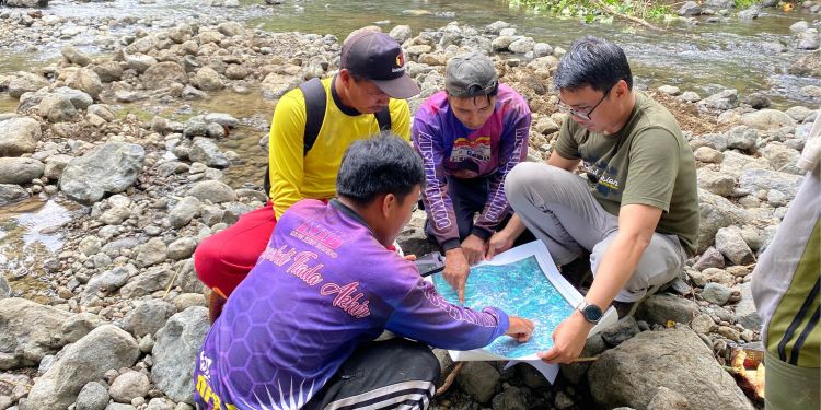 Farmers locating spring water sources the river and land affected by drought using a printed map and mobile app