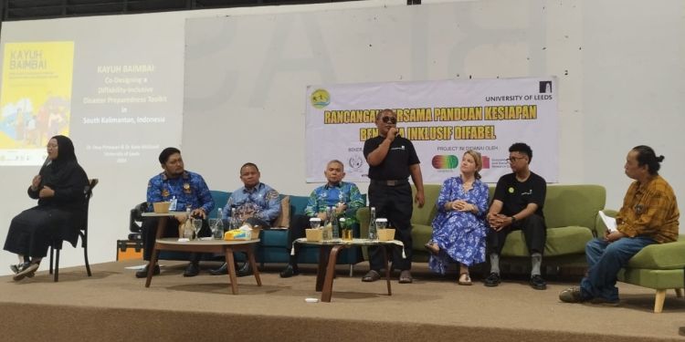 A group of researchers and practitioners sit on a stage, discussing the Diffability Inclusive Disaster Preparedness Toolkit. A sign language interpreter sits in front of them.