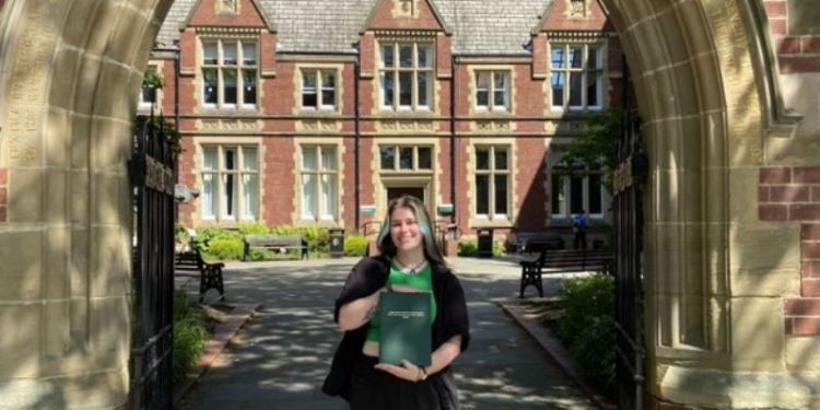 Isabelle Wicks holding her dissertation outside the Great Hall, University of Leeds campus.