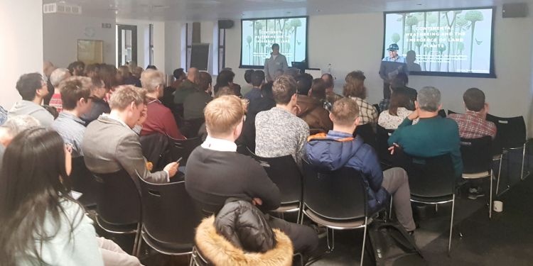 An audience sitting on chairs, watching a presentation