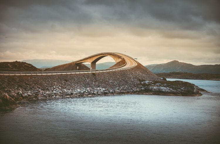 A picturesque view of a Norway sea landscape with a large curved bridge.