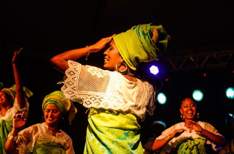 A woman dancing in a spotlight, surround by other dancing.