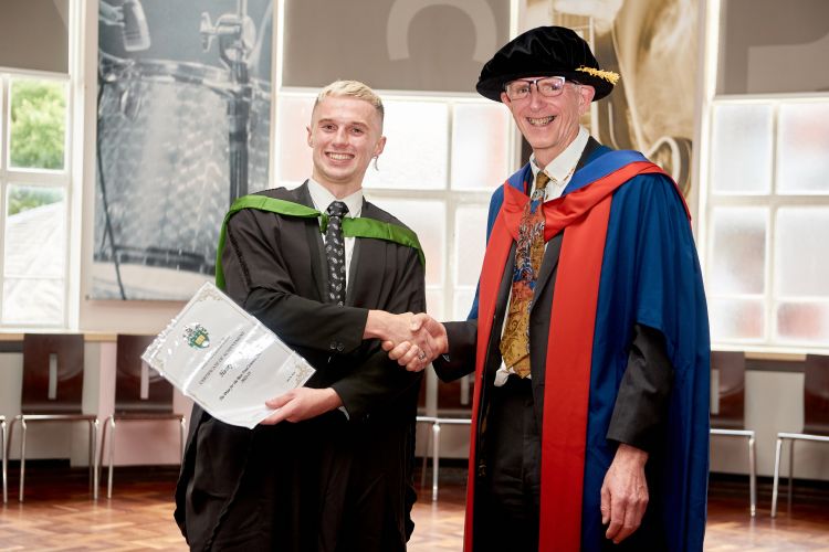 Alan Mackie shaking hands with a PhD student as they graduate.