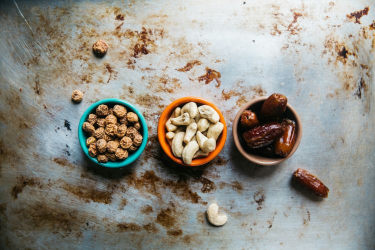 Three small bowls of nuts and dates